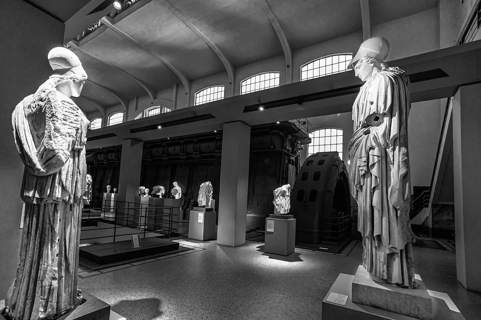 Statue antiche di Atena esposte nella Sala Macchine della Centrale Montemartini, con i motori sullo sfondo